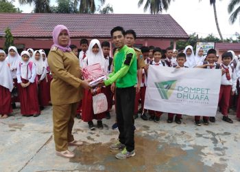 Staf Divisi Program Sosial dan Dakwah DD Sumsel, Ahabba Tholibin menyerahkan bantuan seragam sekolah kepada siswa yang diterima Kepala SD 02, Desa Tanda Raja, Kecamatan Kikim Timur, Kabupaten Lahat, Selasa (14/01). (ist)