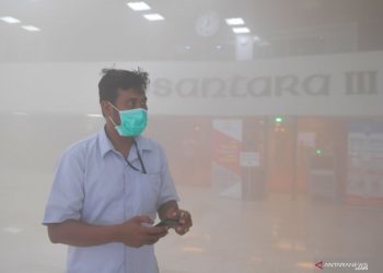 Seorang pegawai berusaha menghindari asap yang memenuhi gedung Nusantara III DPR, Senin (24/2). Foto : Antara