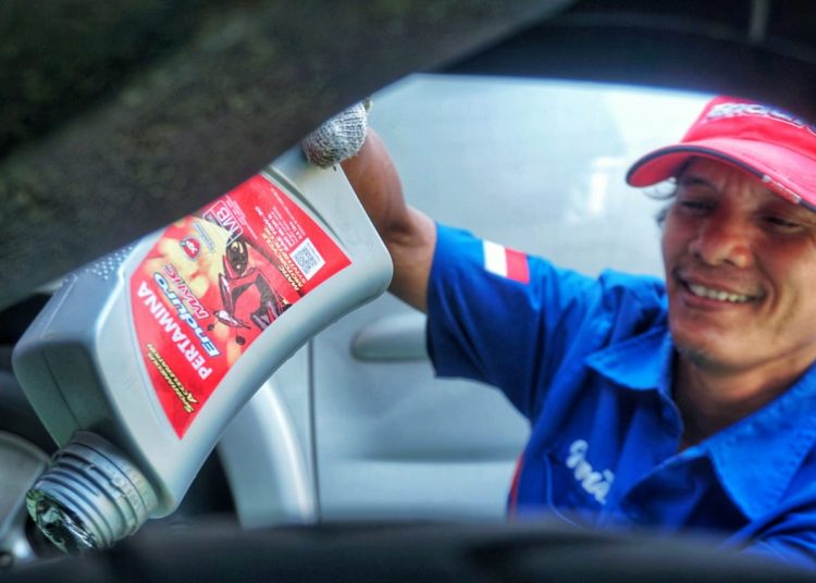 Seorang teknisi gerai Pertamina Lubricants melakukan penggantian oli mobil dengan produk pelumas anak perusahaan Pertamina itu. Di tengah pandemi COVID-19, Pertamina Lubricants menawarkan program ganti oli kendaraan di rumah. (fornews.co/ist)