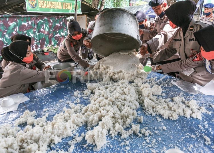 Anggota Polwan menyiapkan nasi yang dimasak di dapur umum untuk dibagikan ke masyarakat terdampak COVID-19. (matakamera/fornews.co/mushaful imam)