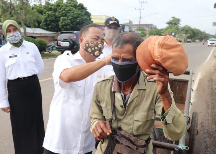 Sekda Muba Apriyadi memasangkan masker kain kepada warga Muba yang melintas di jalanan Kota Sekayu, Senin (20/04). (fornews.co/humas pemkab muba)