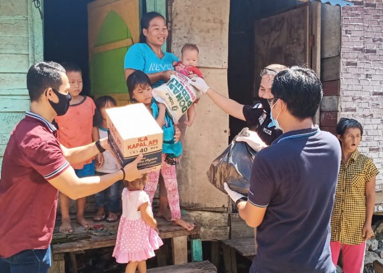 Anggota Sat Res Narkoba Polrestabes Palembang menyapa dan memberikan bantuan paket kebutuhan pokok kepada warga Palembang yang terdampak COVID-19, Rabu (22/04). (fornews.co/ist)