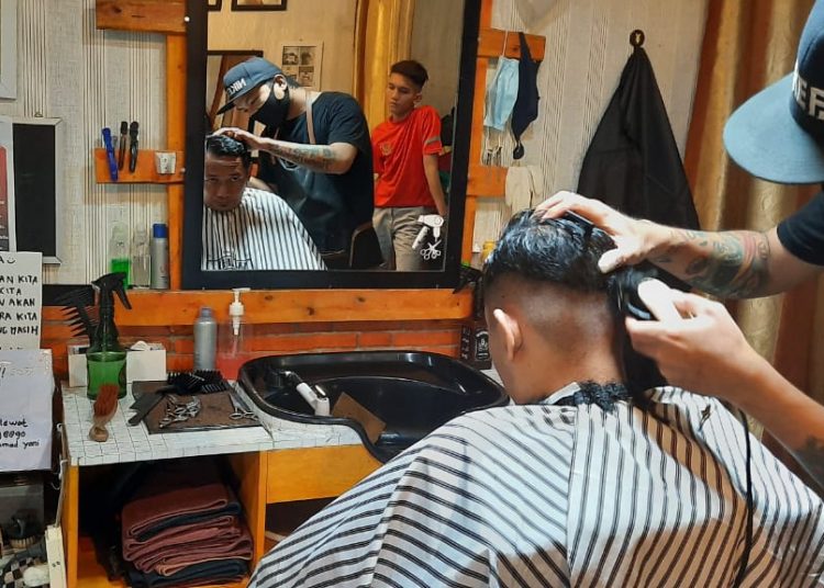Seorang pelanggan sedang dipangkas rambutnya di The Jalu Barbershop, Sabtu (25/04). (fornews.co/rusli gumay)