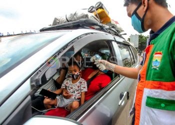 Petugas memeriksa suhu tubuh penumpang di Posko Check Point pintu masuk Palembang. (matakamera/fornews.co/mushaful imam)