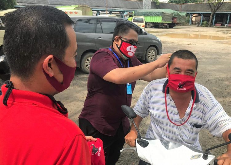 Ketua DPD PDI Perjuangan Sumsel, Giri Ramanda Kiemas membantu memasangkan masker kepada warga di di kawasan Pasar Perumnas Sako, Palembang, Sabtu (18/4). (fornews.co/ist)