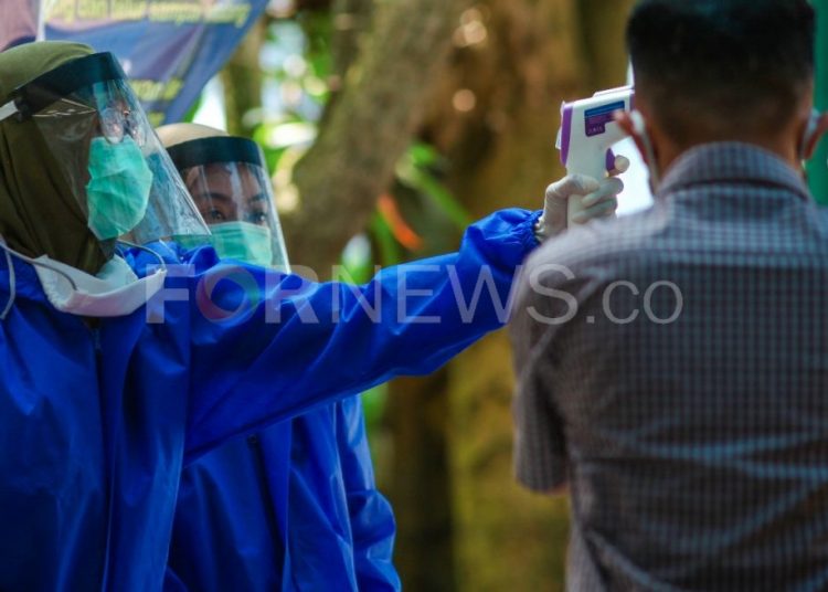 Dua petugas Puskesmas Talang Betutu dengan pakaian APD bertugas di Posko Pantau COVID-19 di Terminal Alang Alang Lebar, Kota Palembang, Senin (20/04/2020). (matakamera/fornews.co/mushaful imam)