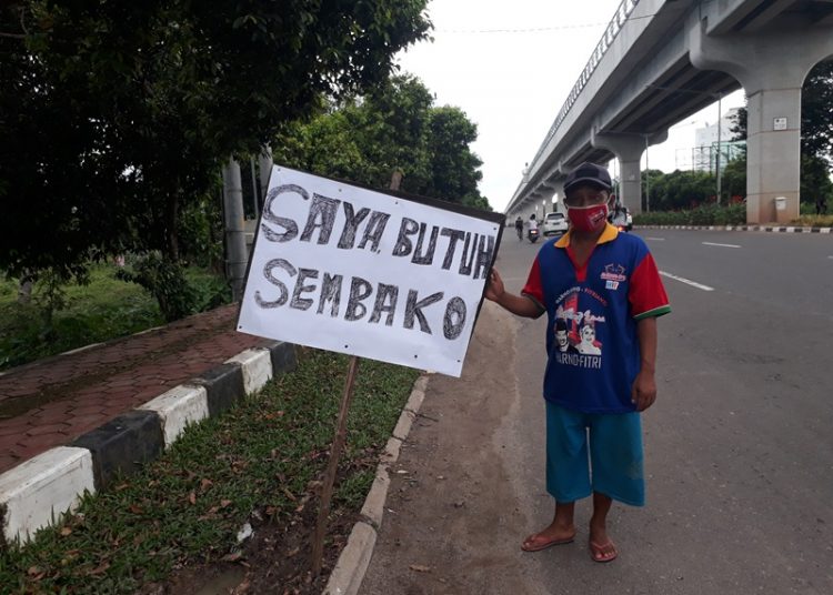 Zuki berdiri di pinggir jalan mengharapkan bantuan sembako dari Pemerintah maupun pengendara yang melintas karena tak lagi mampu membeli bahan pokok sebagai imbas pandemi COVID-19. (fornews.co/rusli gumay)