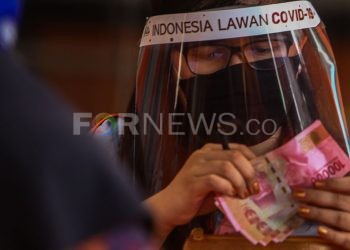 Petugas PT Pos Indonesia menghitung uang Bantuan Sosial Tunai sebelum diberikan ke warga yang terdampak COVID-19. (matakamera/fornews.co/mushaful imam)
