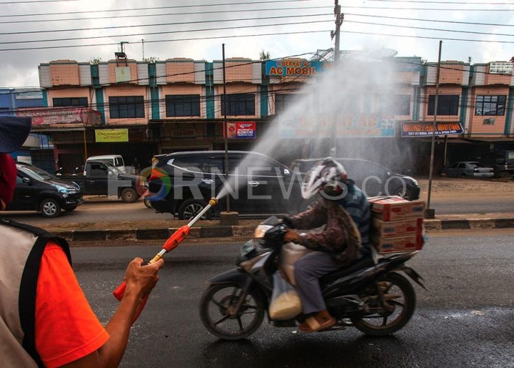 Petugas check point menyemprotkan cairan disinfektan ke pengendara yang melintas. (matakamera/fornews.co/mushaful imam)
