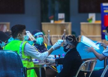 Petugas Bandara SMB II memeriksa suhu tubuh calon penumpang yang akan berangkat. (matakamera/fornews.co/mushaful imam)