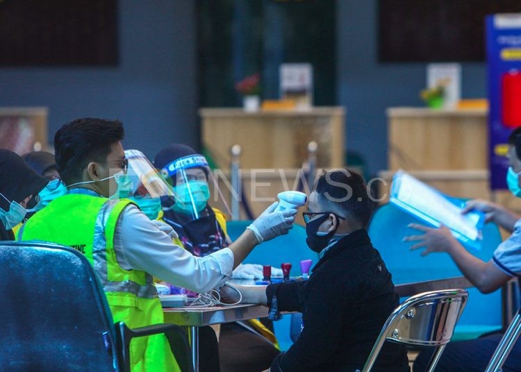 Petugas Bandara SMB II memeriksa suhu tubuh calon penumpang yang akan berangkat. (matakamera/fornews.co/mushaful imam)