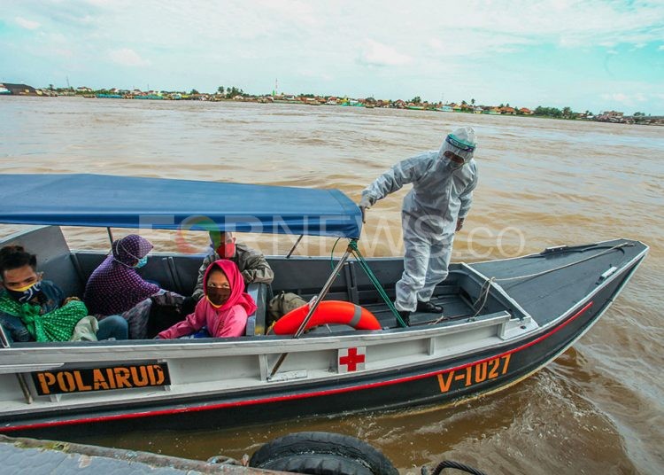 Petugas Polairud Polda Sumsel dari Pangkalan Sandar Upang mengenakan APD lengkap saat mengevakuasi jenazah bayi yang meninggal saat baru dilahirkan dari ibu yang positif COVID-19 dari hasil rapid test di RS Pelabuhan Boom Baru, Kamis (21/05). (fornews.co/mushaful imam)