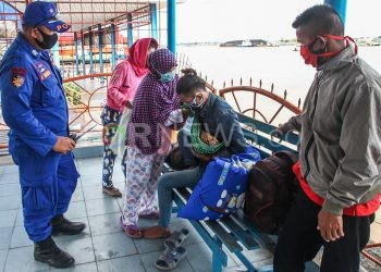 Katim UCPC19 Bripka Hendri Suhendri mengawal bayi dan anggota keluarga menunggu penjemputan. (matakamera/fornews.co/mushaful imam)