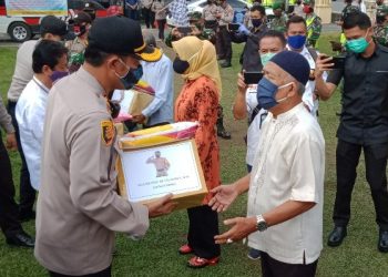 Kapolres OKI saat menyerahkan bantuan sosial kepada salah seorang warga secara simbolis di Mapolres OKI, Jumat (15/05). (Foto : fornews.co / rif)