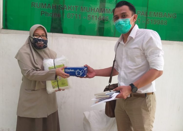Ketua AJI Palembang Prawira Maulana saat menyerahkan bantuan baju hazmat dan masker yang diterima Kepala Logistik COVID-19 RS Muhammadiyah Palembang Ida Kesuma, Selasa (09/06). (fornews.co/aji palembang)