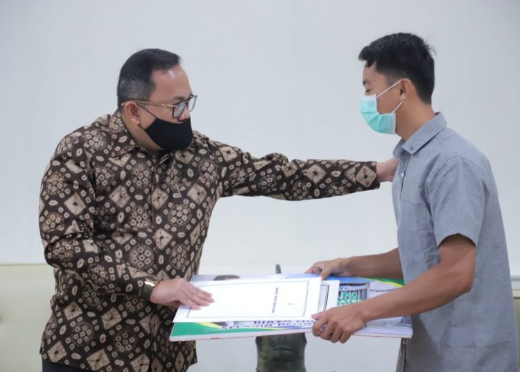 Bupati Muba Dodi Reza Alex saat menyerahkan secara simbolis bantuan biaya operasi kepada Ilham, orang tua Bunga, bayi penderita meningokel, Jumat (19/06). (fornews.co/humas pemkab muba)