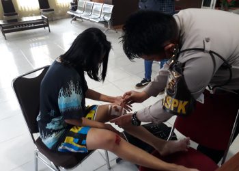 Petugas piket SPKT Polrestabes Palembang mengobati luka Diana yang menjadi korban penjambretan saat melapor ke Polrestabes Palembang, Senin (01/06). (fornews.co/rusli gumay)