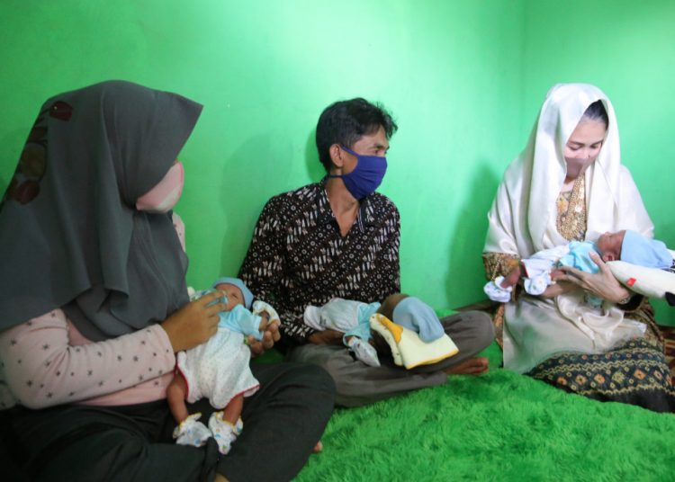 Ketua TP PKK Kabupaten Muba Thia Yufada menggendong satu dari tiga bayi kembar anak pasangan Edi dan Reni di Desa Toman, Kecamatan Babat Toman, Selasa (09/06). (fornews.co/humas pemkab muba)