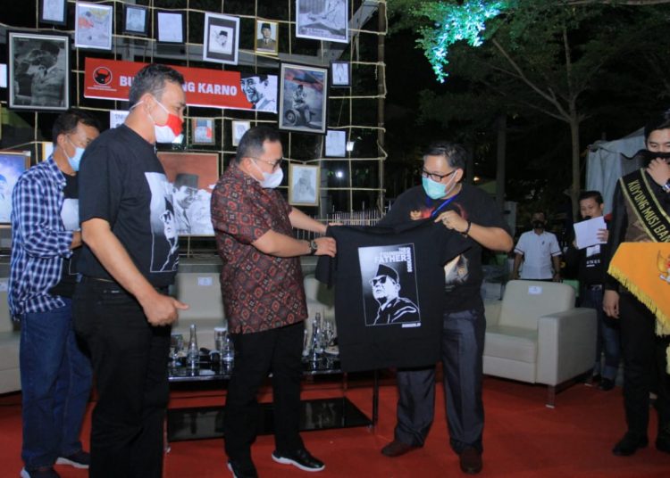 Ketua DPD PDI Perjuangan Sumsel Giri Ramanda Kiemas menyerahkan kaos bergambar Bung Karno kepada Bupati Muba Dodi Reza Alex pada malam puncak peringatan Bulan Bung Karno di waterfront Sekayu, Senin (27/07) malam. (fornews.co/humas pemkab muba)