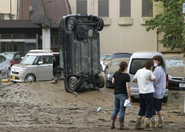 Sebuah mobil berdiri secara vertikal di jalan berlumpur setelah tersapu banjir, di Hitoyoshi, prefektur Kumamoto, Jepang barat daya, Minggu, 5 Juli 2020. Foto: Istimewa/AP