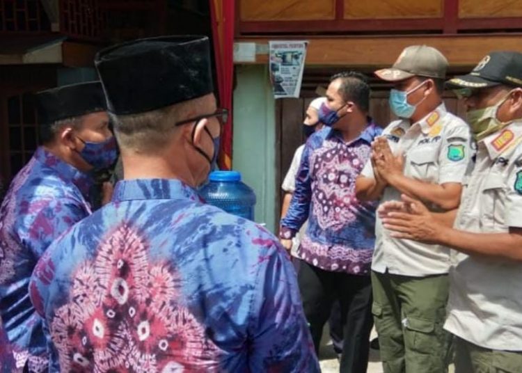 Petugas Satpol PP Kabupaten Muba berbincang dengan perwakilan keluarga yang menggelar hajatan pernikahan untuk memastikan penerapan protokol kesehatan, Sabtu (17/10). (fornews.co/humas pemkab muba)