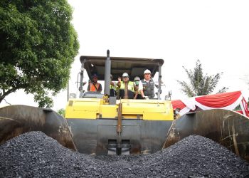 Gubernur Sumsel Herman Deru dan Bupati Muba Dodi Reza Alex menaiki alat berat untuk melakukan uji gelar aspal karet di Desa Teladan, Sekayu, Kabupaten Muba, Senin (26/10). (fornews.co/humas pemkab muba)