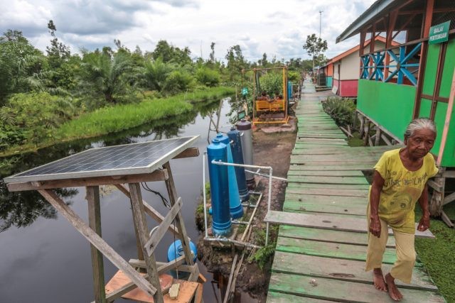 Ibu Timah, generasi ketiga Suku Anak Dalam (SAD) melintas di jalan desa yang dilengkapi fasilitas panel solar, tabung filterisasi air bersih dan balai pertemuan. (matakamera/fornews.co/mushaful imam)