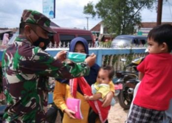 Personel Kodim 0402/OKI saat memasangkan masker kepada salah seorang warga. (IST)