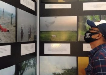 Salah satu pengunjung memperhatikan foto tentang karhutla di Pameran Foto Jurnalistik Kilas Balik 2018-2019+COVID 19, di Atrium OPI Mall Palembang, Kamis (3/12) sore. (fornews.co/ist)