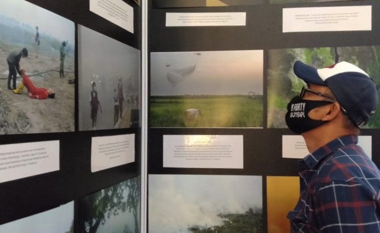 Salah satu pengunjung memperhatikan foto tentang karhutla di Pameran Foto Jurnalistik Kilas Balik 2018-2019+COVID 19, di Atrium OPI Mall Palembang, Kamis (3/12) sore. (fornews.co/ist)