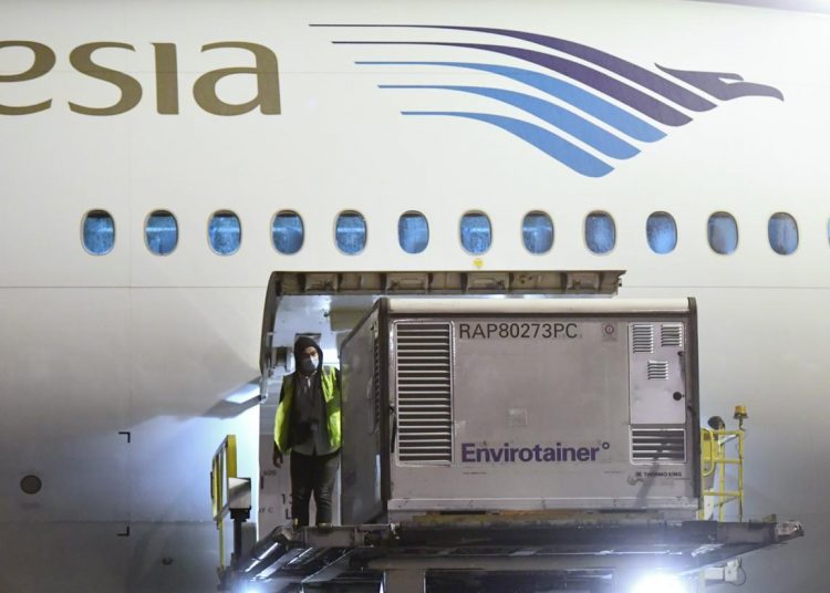 Seorang petugas mengeluarkan envirotainer berisi vaksin COVID-19 Sinovac setibanya di Bandara Internasional Soekarno - Hatta, Minggu malam (6/12). (fornews.co/bpmi setpres/muchlis jr)