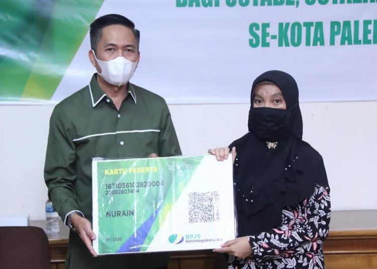 Ketua ISNU Palembang Ratu Dewa menyerahkan secara simbolis kartu anggota BPJS Ketenagakerjaan kepada salah seorang dari 258 pekerja informal yang didaftarkan, Sabtu (5/12). (fornews.co/bakohumas palembang)