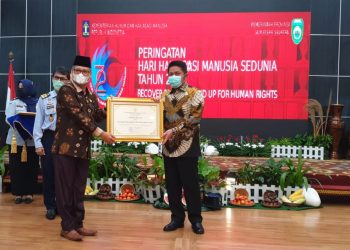 Staf Ahli Bidang Politik Hukum dan Pemerintahan Pemkab Muba, Ibnu Saad saat menerima Penghargaan Kabupaten Peduli HAM dari Kemenkum-HAM yang diserahkan Gubernur Sumsel Herman Deru di Griya Agung Palembang, Senin (14/12). (fornews.co/humas pemkab muba)