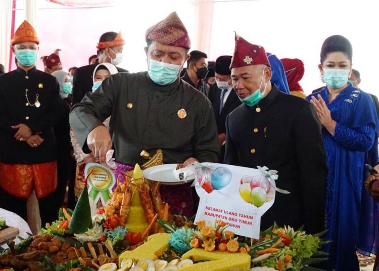 Gubernur Sumsel Herman Deru didampingi Bupati OKU Timur Kholid Mawardi memotong tumpeng pada peringatan HUT ke-17 Kabupaten OKU Timur, Senin (18/1/2021). (fornews.co/humas provinsi sumsel)