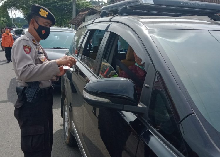 Petugs yang berjaga di salah satu titik saat memeriksa identitas pengendara yang hendak meintas. Pengendara yang akan menuju destinasi wisata akan diarahkan untuk putar balik. (IST)