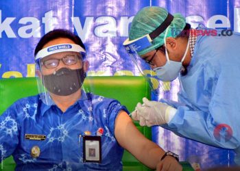 SEORANG petugas dari tim tenaga kesehatan sedang melakukan vaksinasi kepada Wakil Wali Kota Yogakarta, Heroe Poerwadi, di Rumah Sakit Pratama, Jum'at (15/1/2021). (foto fornews.co)