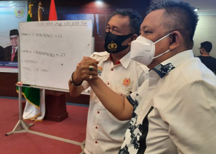 Anton Nurdin salam komando dengan pesaingnya Arbain Semendawai usai terpilih sebagai Ketua KONI Kota Palembang pada Musorkotlub di Ruang Parameswara Pemkot Palembang, Minggu (3/1/2021). (fornews.co/humas koni sumsel)