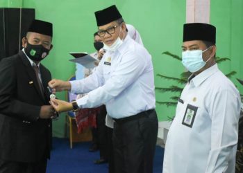 Staf Ahli Bupati Bidang Politik Hukum dan Pemerintahan Setda Kabupaten Muba, Ibnu Sa’ad menyerahkan penghargaan kepada pegawai kantor Kemenag Muba pada Upacara Hari Amal Bakti (HAB) Kementerian Agama ke-75 tahun 2021 di Aula Kantor Kemenag Muba, Selasa (5/1/2021). (fornews.co/humas pemkab muba)