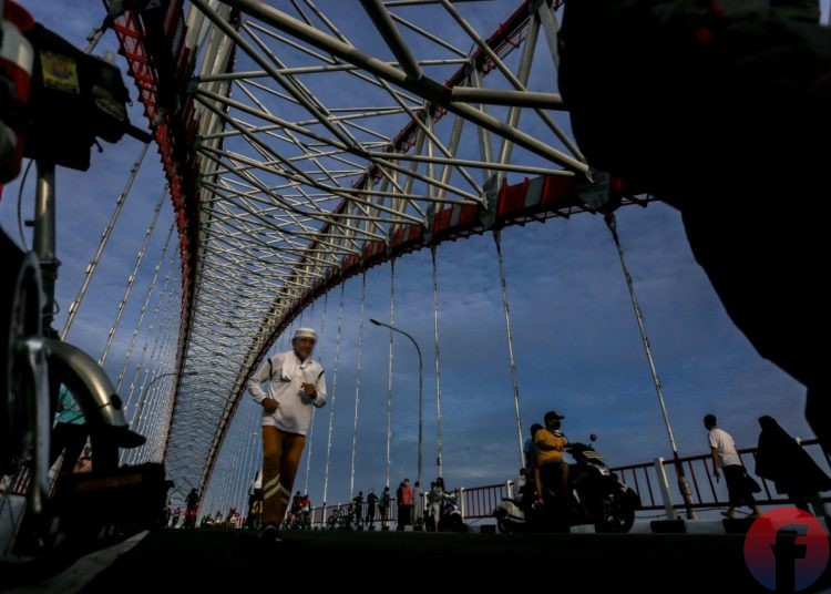 Dengan mengunakan face shield warga berolahraga lari melintas di jembatan. (matakamera/fornews.co/mushaful imam)