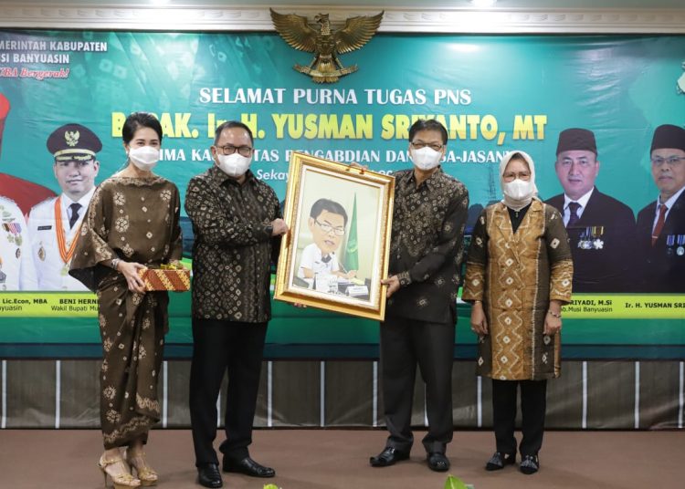 Bupati Muba Dodi Reza Alex menyerahkan lukisan kepada Yusman Sriyanto yang memasuki masa purna tugas pada pelepasan di Auditorium Pemkab Muba, Jumat (15/1/2021). (fornews.co/humas pemkab muba)