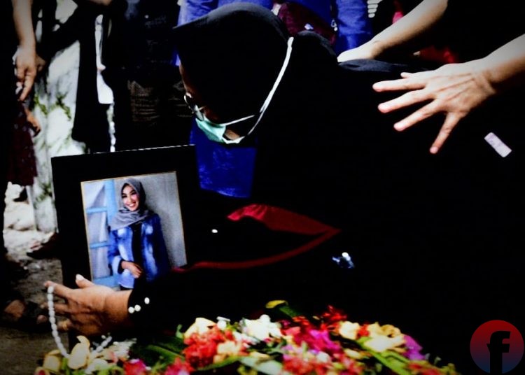 Yusrilanita, ibunda Indah Halimah Putri memeluk foto anaknya di atas pusara usai dimakamkan. (matakamera/fornews.co/mushaful imam)