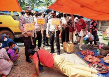Petugas Polsek Rambang Lubai memberikan sanksi fisik kepada warga yang kedapatan melanggar protokol kesehatan karena tidak memakai masker saat melakukan kegiatan yustisi di Kalangan Desa Karang Agung, Kecamatan Lubai Ulu, Kabupaten Muara Enim, Sabtu (27/2/2021). (fornews.co/humas polsek rambang lubai)