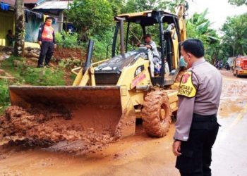 Alat berat membersihkan tanah yang menutupi badan jalan di Desa Kebur, Kecamatan Tiang Pumpung Kepungut, Kabupaten Musi Rawas, Sabtu (13/2/2021). (fornews.co/humas polres mura)