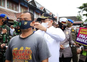 Bupati Muba Dodi Reza Alex memakaikan masker ke seorang pengunjung Pasar Perjuangan, Rabu (3/2/2021). (fornews.co/humas pemkab muba)