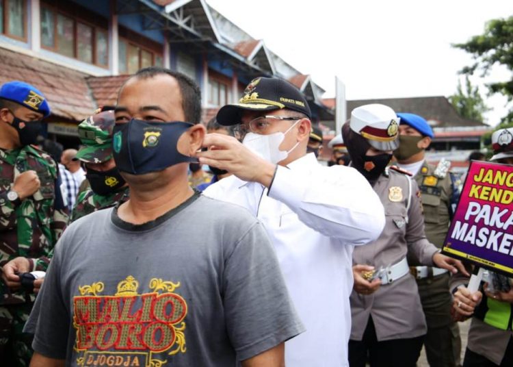 Bupati Muba Dodi Reza Alex memakaikan masker ke seorang pengunjung Pasar Perjuangan, Rabu (3/2/2021). (fornews.co/humas pemkab muba)
