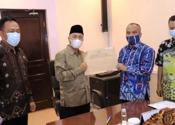 Sekda Muba Apriyadi menerima berkas administrasi kepegawaian Pemkab Muba yang diserahkan Kepala Kantor Regional VII Badan Kepegawaian Negara (BKN) Palembang, Margi Prayitno, di Ruang Rapat Sekda, Jumat (5/2/2021). (fornews.co/humas pemkab muba)