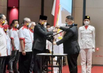 Ketua Umum KONI Sumsel Hendri Zainuddin menyerahkan pataka KONI OKU kepada Supriadi Jazid yang dilantik sebagai Ketua KONI OKU periode 2020-2024 di ballroom Hotel The Zuri Batuaraja, Sabtu (6/2/2021). (fornews.co/humas koni sumsel)