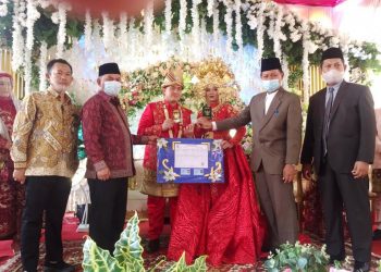 Pasangan pengantin baru Sumantri dan Mega Dirgantara mendapatkan kado dari Pemkab OKI berupa paket 3 in 1 dokumen kependudukan pada resepsi pernikahan mereka, Minggu (7/2/2021). (fornews.co/humas pemkab oki)