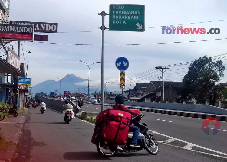 SEORANG kurir berkendara di jalan lingkar Timur (Rigroad) harus tetap bekerja meski pembatasan kegiatan masyarakat di Yogya diperpanjang. (foto fornews.co/adam)