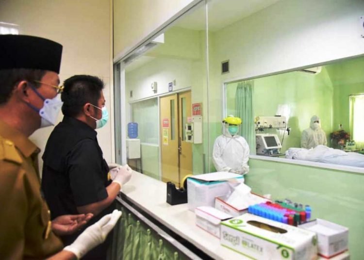Gubernur Sumsel Herman Deru didampingi Wali Kota Palembang Harnojoyo saat mendoakan jenazah Bupati OKU Kuryana Azis dari balik kaca ruang perawatan RS RK Charitas Palembang, Senin (8/3/2021). (fornews.co/humas provinsi sumsel)